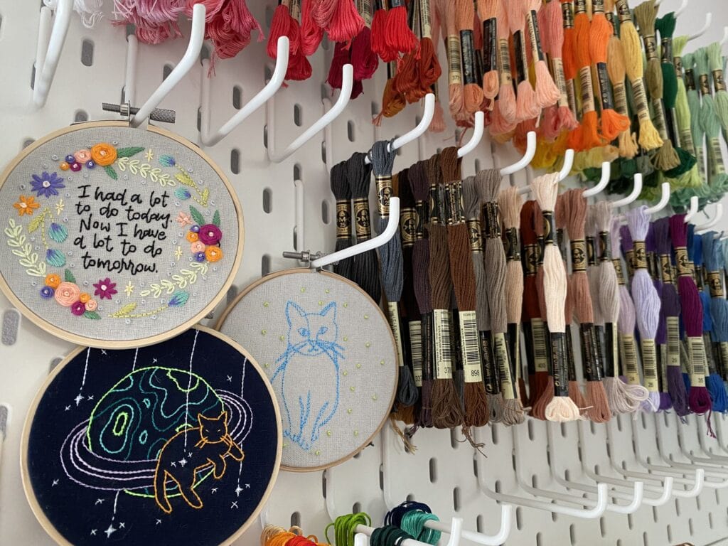A display of embroidery hoops and threads hanging on a wall.